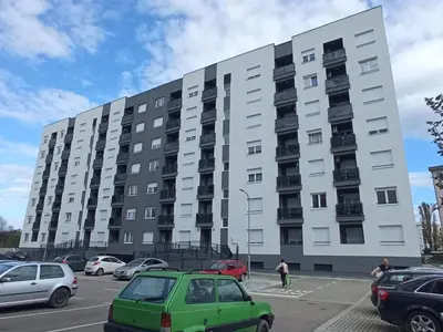 a large white building with cars parked in a parking lot at Stan na dan Apartman ADA Banjaluka in Banja Luka