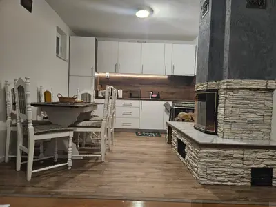 a kitchen with a table and a stone fireplace at Planinska kuća Ruža in Kupres