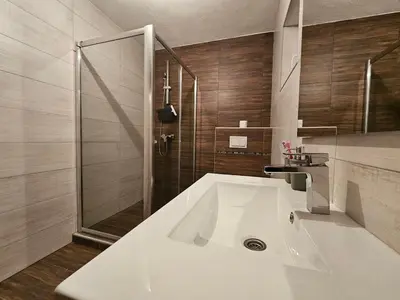 a bathroom with a large white sink and a shower at Planinska kuća Ruža in Kupres