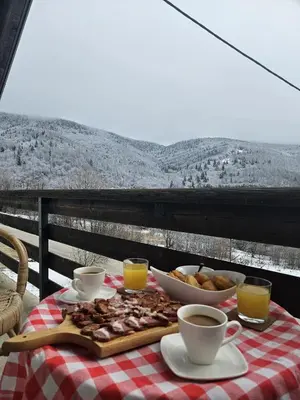 a table with a plate of food and cups of coffee at Planinska kuća Ruža in Kupres