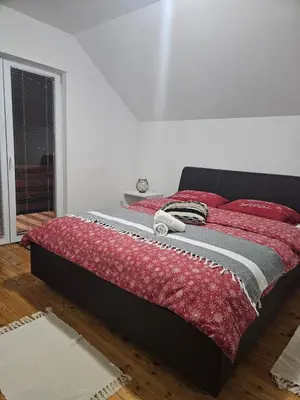 a bed with a red blanket on top of it at Planinska kuća Ruža in Kupres