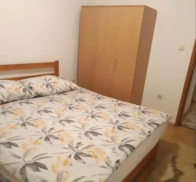 a bedroom with a bed and a wooden cabinet at Apartman Iva in Kupres