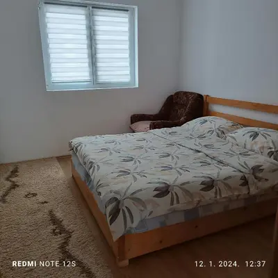 a bedroom with a bed and a chair and a window at Apartman Iva in Kupres