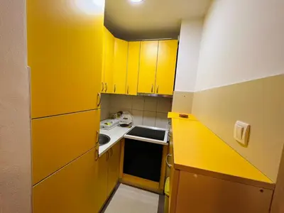 a small kitchen with yellow cabinets and a sink at Apartman Stefan in Banja Luka