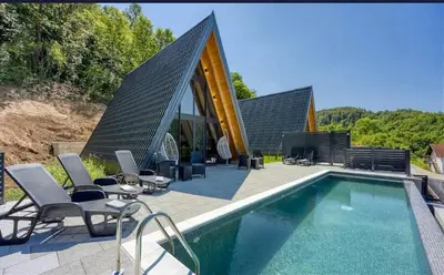 a swimming pool with chairs and a house at UNA RESORT in Bosanska Krupa