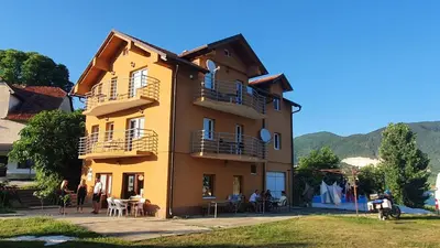 a yellow building with people sitting outside of it at Apartmani Šćit in Šćit