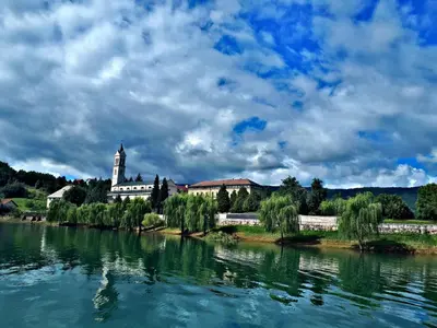 a building with a clock tower next to a river at Apartmani Šćit in Šćit