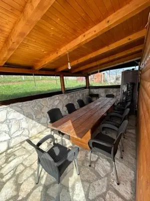 a large wooden table and chairs on a patio at Jerry's Cottage Banja Luka in Banja Luka