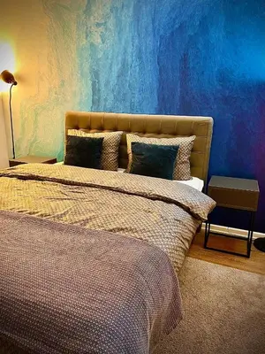 a bedroom with a bed with a blue wall at Apartman BRONX Prijedor in Prijedor