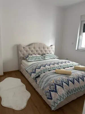 a bedroom with a bed with a blanket and a rug at Restoran&Motel and apartmants Lovacka prica in Tešanj
