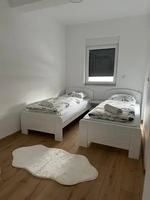 two beds in a white room with a window at Restoran&Motel and apartmants Lovacka prica in Tešanj