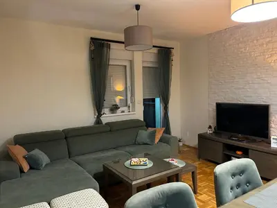 a living room with a green couch and a tv at Apartman Obala in Bosanska Gradiška