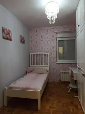 a small bedroom with a bed and a chandelier at Apartman Obala in Bosanska Gradiška