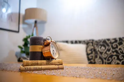 a clock sitting on top of a table with a book at Kuća za odmor Mali raj-Kupres in Kupres