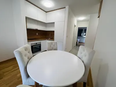 a white kitchen with a white table and chairs at Apartman Maja Lux in Banja Luka