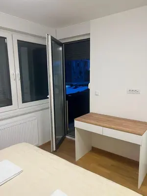 a bedroom with a sliding glass door with a desk at Apartman Maja Lux in Banja Luka