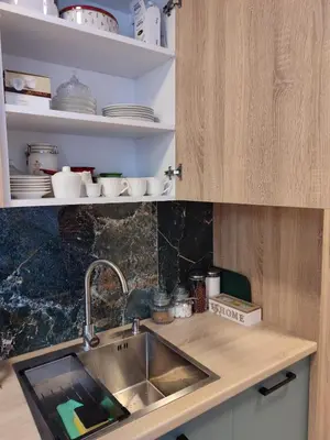 a kitchen with a sink and a shelf with dishes at Tuzlanska Panonica in Tuzla