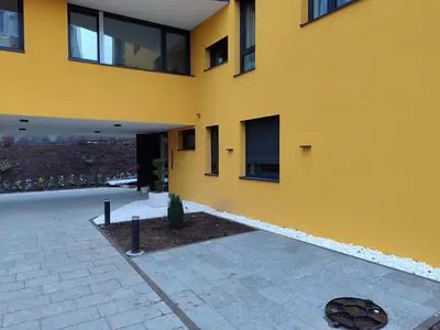 a yellow building with a courtyard in front of it at Panonika Tuzla in Tuzla