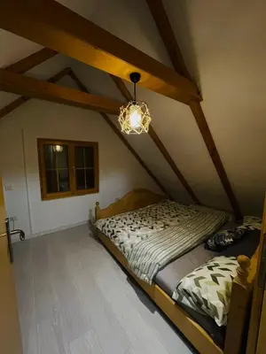 a bedroom with a bed in a attic with a chandelier at Vikendica Bajka in Banja Luka