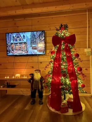 a santa clause standing next to a christmas tree at Vikendica Bajka in Banja Luka