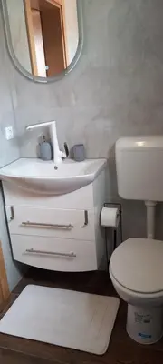 a bathroom with a sink and a toilet and a mirror at Vikendica Striček in Kupres