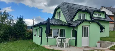 a green house with two chairs and a table at Vikendica Striček in Kupres