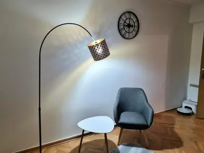 a room with a lamp and a chair and a clock at Apartment Urban Nest in Zenica