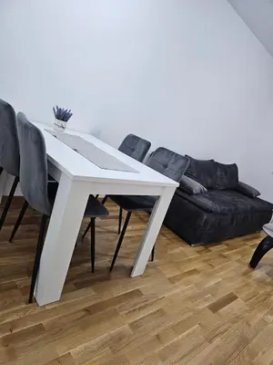a white dining room table with black chairs and a couch at Apartman Urukalo in Rebrovac