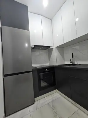 a kitchen with white cabinets and a stainless steel refrigerator at Apartman Urukalo in Rebrovac