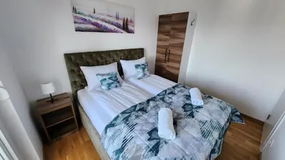 a bedroom with a bed with white sheets and blue pillows at Ada Nostra in Banja Luka