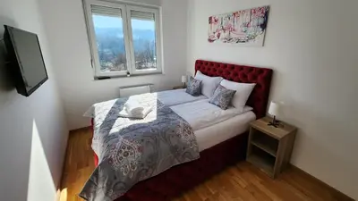 a bedroom with a bed with a red headboard and a window at Ada Nostra in Banja Luka