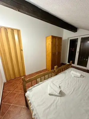 a bedroom with a bed with white sheets and a window at Apartmani Ivan in Kupres