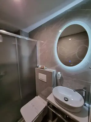 a bathroom with a sink and a round mirror at Motel Bor in Vitez