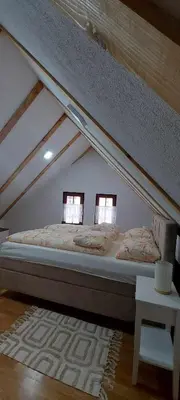 a bed in a attic room with two windows at Villa Ruža Vareš in Vareš