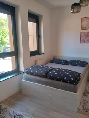 a bed in a room with two windows at AS apartman Panonica in Tuzla