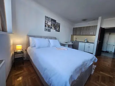 a bedroom with a large white bed and a kitchen at Mrakovica 1 in Prijedor