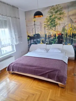 a bedroom with a bed with a painting on the wall at San apartment in Banja Luka