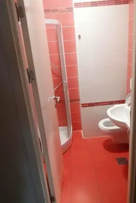 a red bathroom with a toilet and a sink at San apartment in Banja Luka
