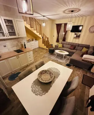 a kitchen and a living room with a dining table at Planinska kuća Mali Raj in Mrkonjić Grad