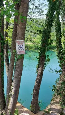 a sign on two trees in front of a lake at Unatime.Krupa in Bosanska Krupa