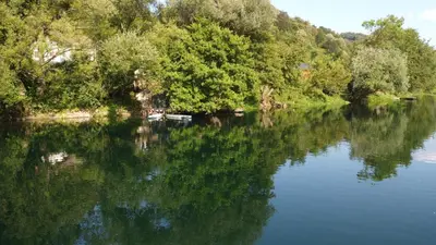 a river with trees reflecting in the water at Unatime.Krupa in Bosanska Krupa