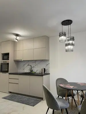 a kitchen with white cabinets and a table with chairs at Apartman Marina stan na dan in Prijedor