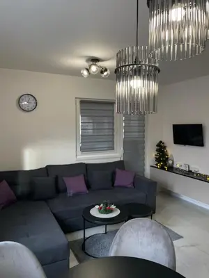 a living room with a couch and a table and chandeliers at Apartman Marina stan na dan in Prijedor