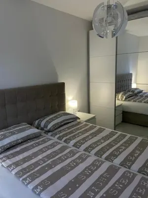 a bedroom with a large bed and a mirror at Apartman Marina stan na dan in Prijedor