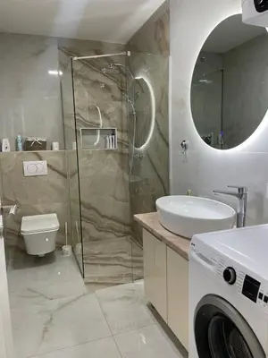 a bathroom with a shower and a sink and a washing machine at Apartman Marina stan na dan in Prijedor