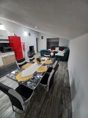 a dining room with a table and chairs and a living room at Apartman Varcar in Bihać