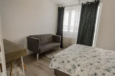 a bedroom with a chair and a bed and a window at 5 min Apartment in Banja Luka
