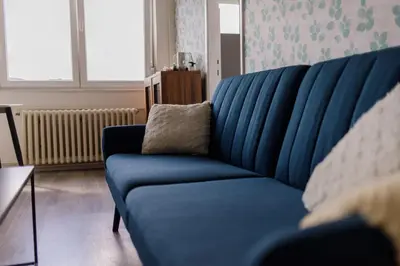 a blue couch in a living room with a pillow at 5 min Apartment in Banja Luka