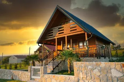 a wooden house with a fence and a stone wall at Vikendica Ivana in Livno