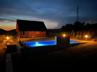 a barn with blue lights in front of a building at Vikendica Ivana in Livno